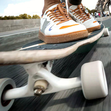 dettaglio truck longboard con ruote e tavola in movimento su asfalto durante riding urbano